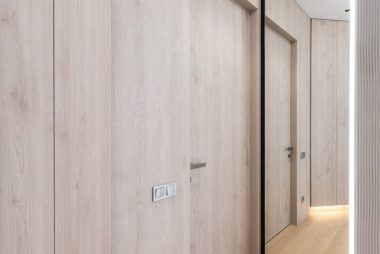 Interior of light empty corridor with door next to mirror in modern apartment